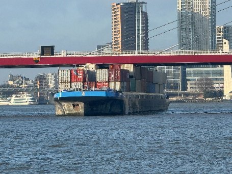 Een beladen binnenvaartschip onder de Willemsbrug in Rotterdam